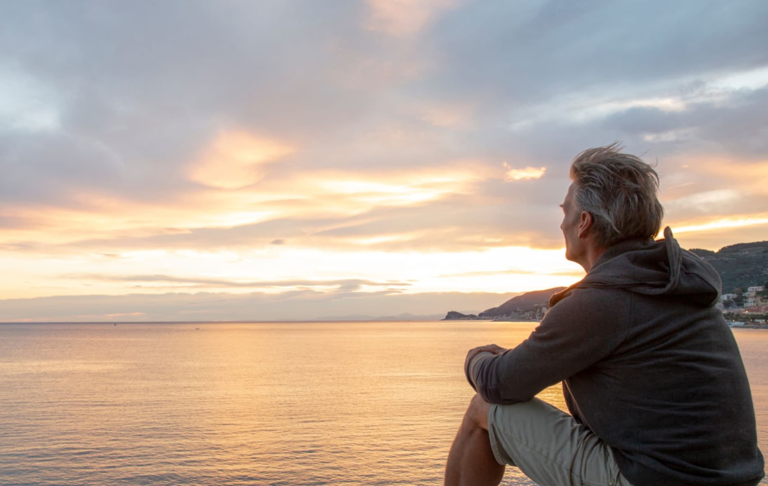 Homme regardant l’horizon au couchant, face à la mer